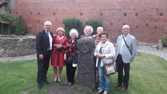 Niektórzy uczestnicy spotkania zrobili sobie pamiątkowe zdjęcia  na dziedzińcu olsztyńskiego zamku z tzw. „babą pruską” …
